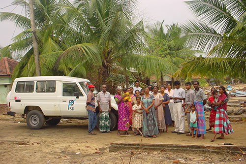 Hommes, femmes et enfants sri-lankais rassemblés devant un véhicule de la FSD après le tsunami de 2004.