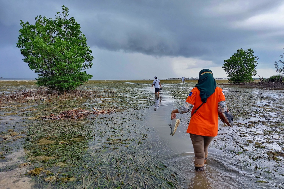 FSD staff and a volunteer traversing tidal flats to get give a risk education session to a nearby village in Barangay division