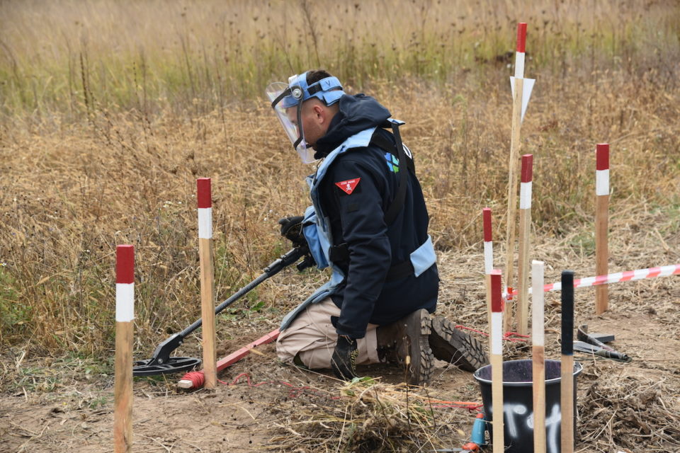 Deminer checking a field for expllosives using his metal detector in Chernihiv, Ukraine