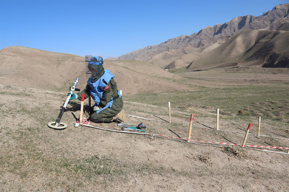 An FSD deminer in blue protective vest and visors conducts manual landmine clearance at Khamadoni