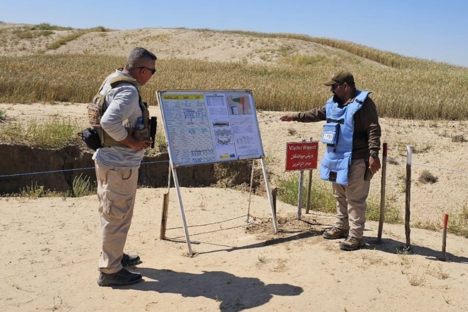 FSD Operator conducting metal detector clearance procedures with Khalidiya village in the background iraq