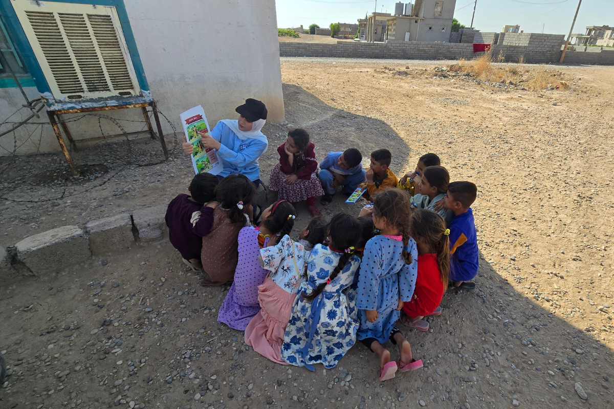 Female staff delivering risk education session to children in Iraq